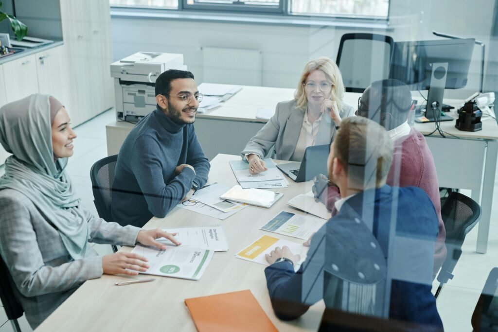 A diverse group of professionals engaged in a meeting at a modern office, promoting teamwork and collaboration.