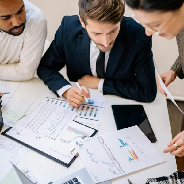 Business professionals collaborating over charts and laptops in an office.